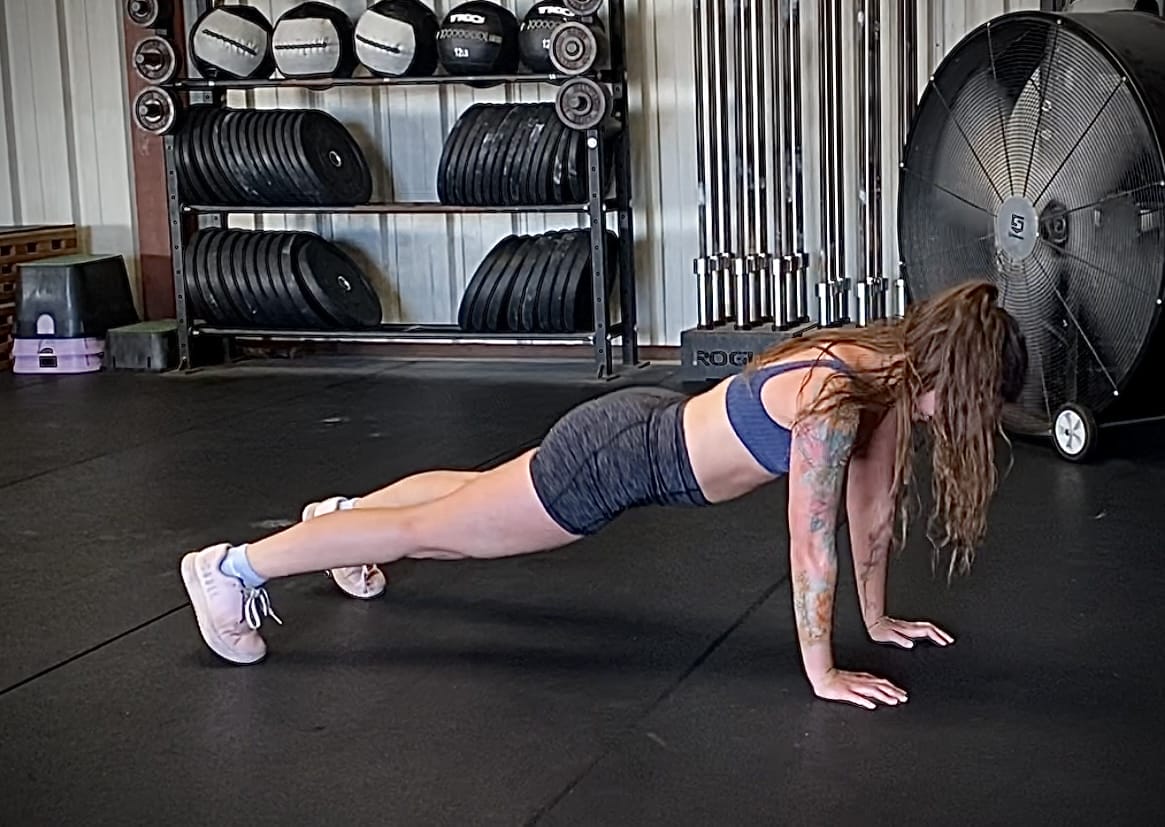 A strong woman with a sleeve tattoo does push ups in her workouts and her arms look great!